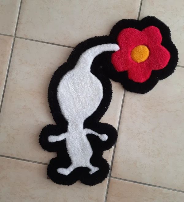 Le tapis a la forme d'un pikmin blanc avec une fleur rose éclos sur la tête. Il est moelleux et fait en laine. Il est de couleur blanche avec un contour noir. La fleur est rose fuschia avec un coeur jaune. Le Pikmin est représenté de coté en train de marcher.